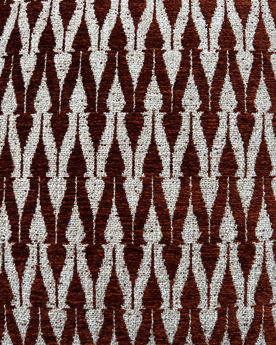 Close-up van het terracotta-met-crème geweven patroon van het Hogaría sierkussen, met een rijk textuurdesign en luxe ambachtelijke afwerking voor hoogwaardige interieurstyling.