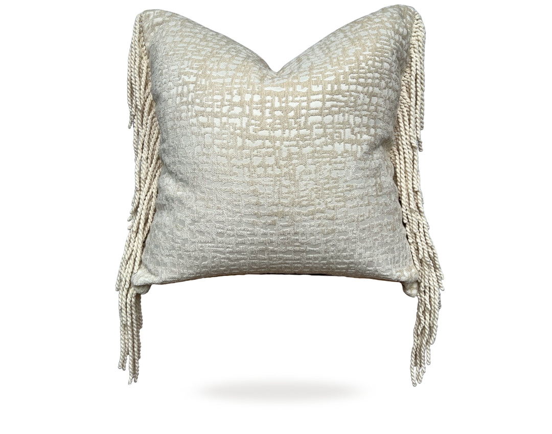 Crèmekleurig Hogaría sierkussen met fijne textuur en lange, gedraaide franjes aan de zijkanten, luxe handgemaakt interieurkussen in zacht neutraal design, perfect voor moderne en warme woonruimtes.